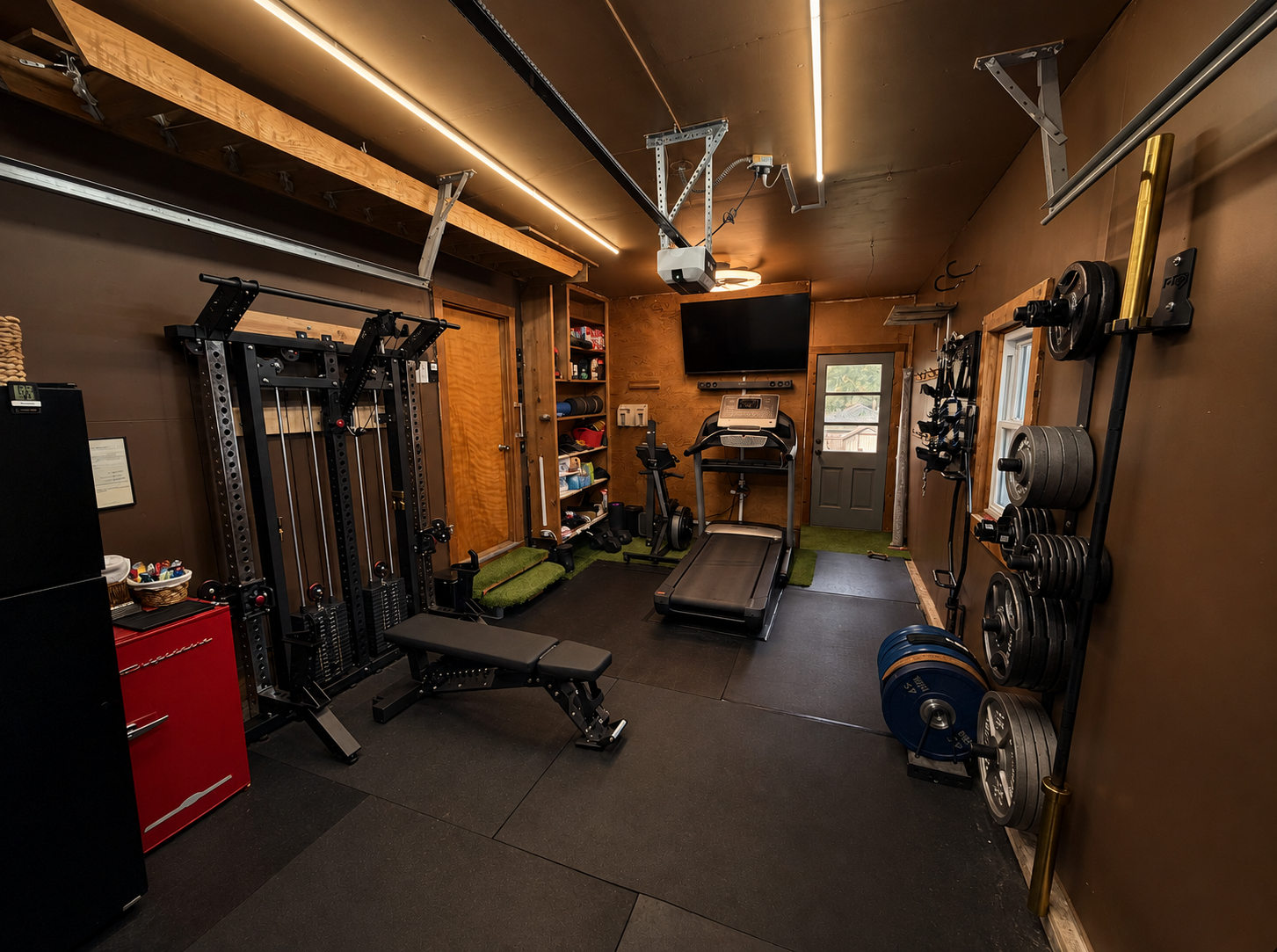 Principle Athletics home-based training studio in Lenexa, with cable trainer, bench, treadmill, and weight storage